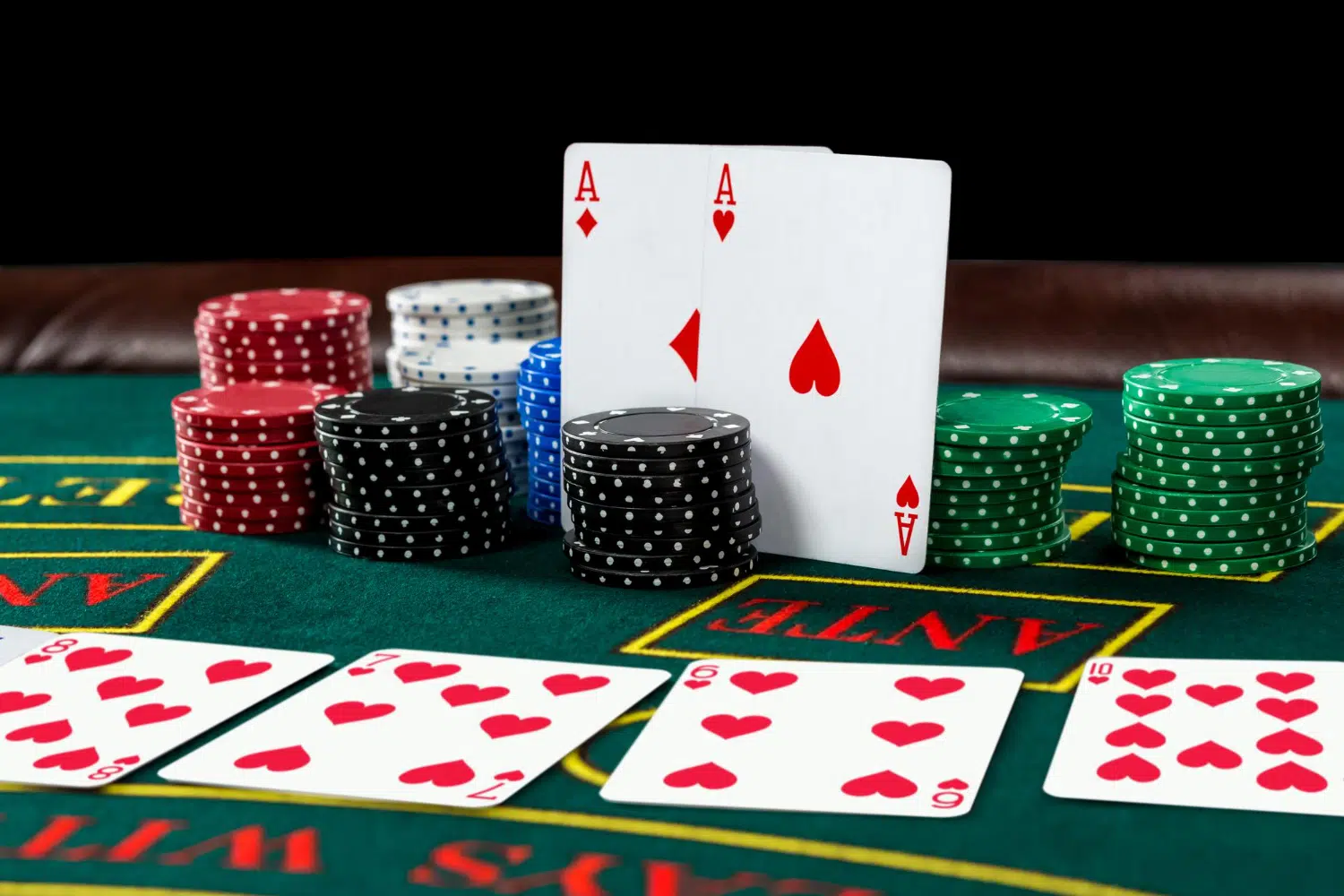 Image of a blackjack table with two aces up, betting chips, and a four-card deck in front
