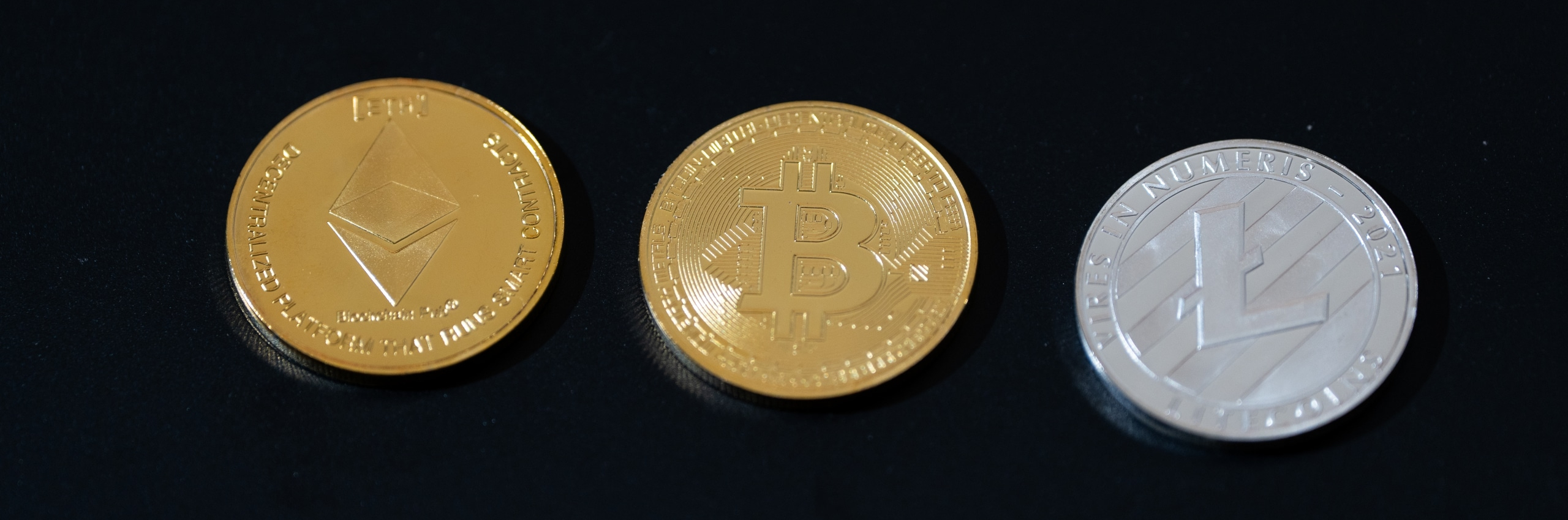 A banner with three types of cryptocurrencies on a black bacckground